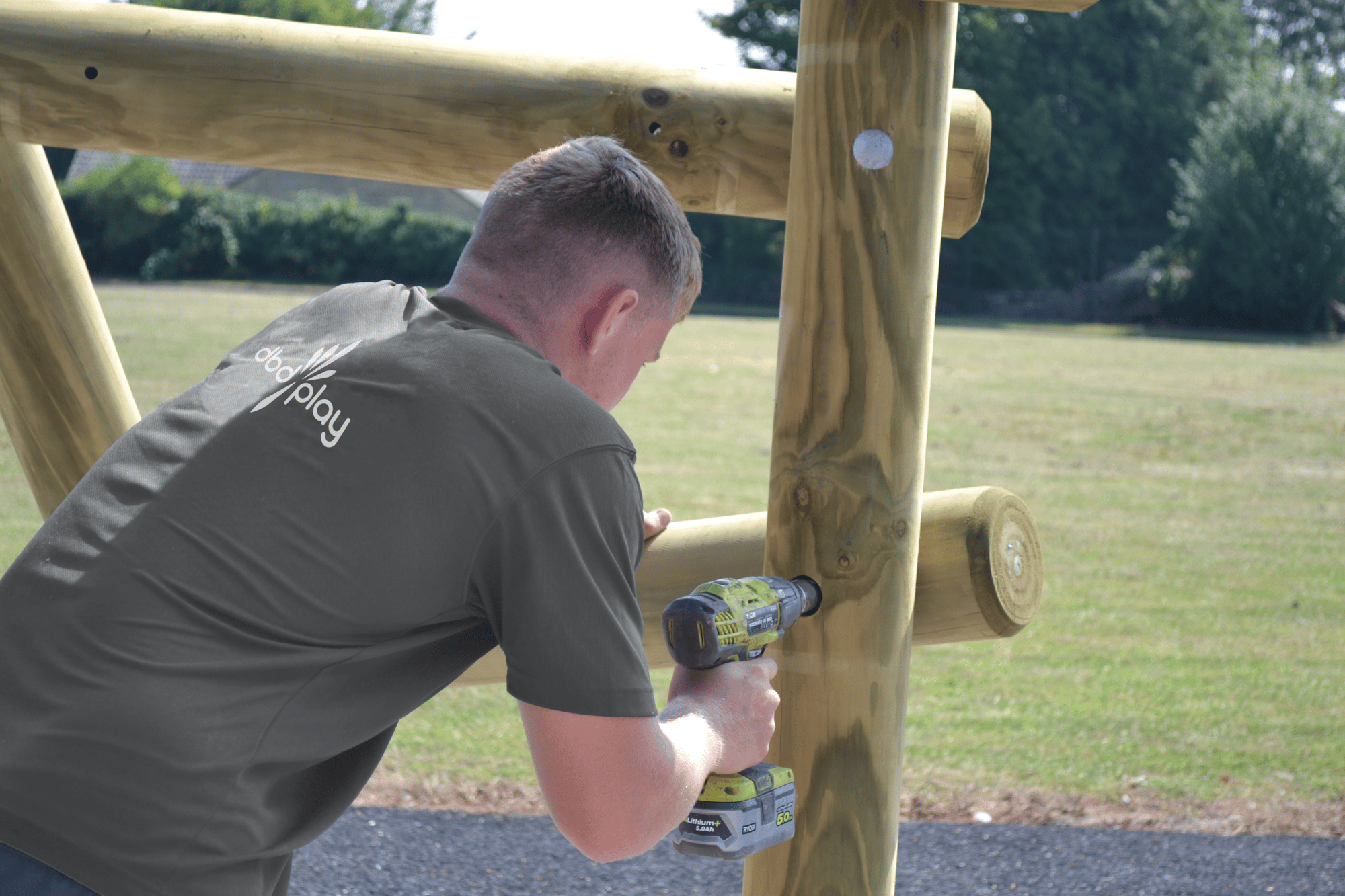 dbdplay employee using impact driver to install play equipment