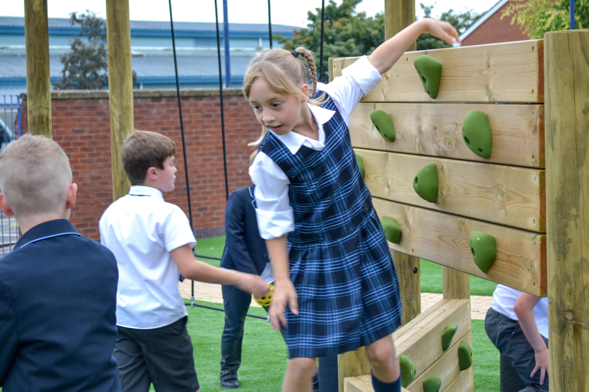 Girl in blue school uniform climbing a wooden structure