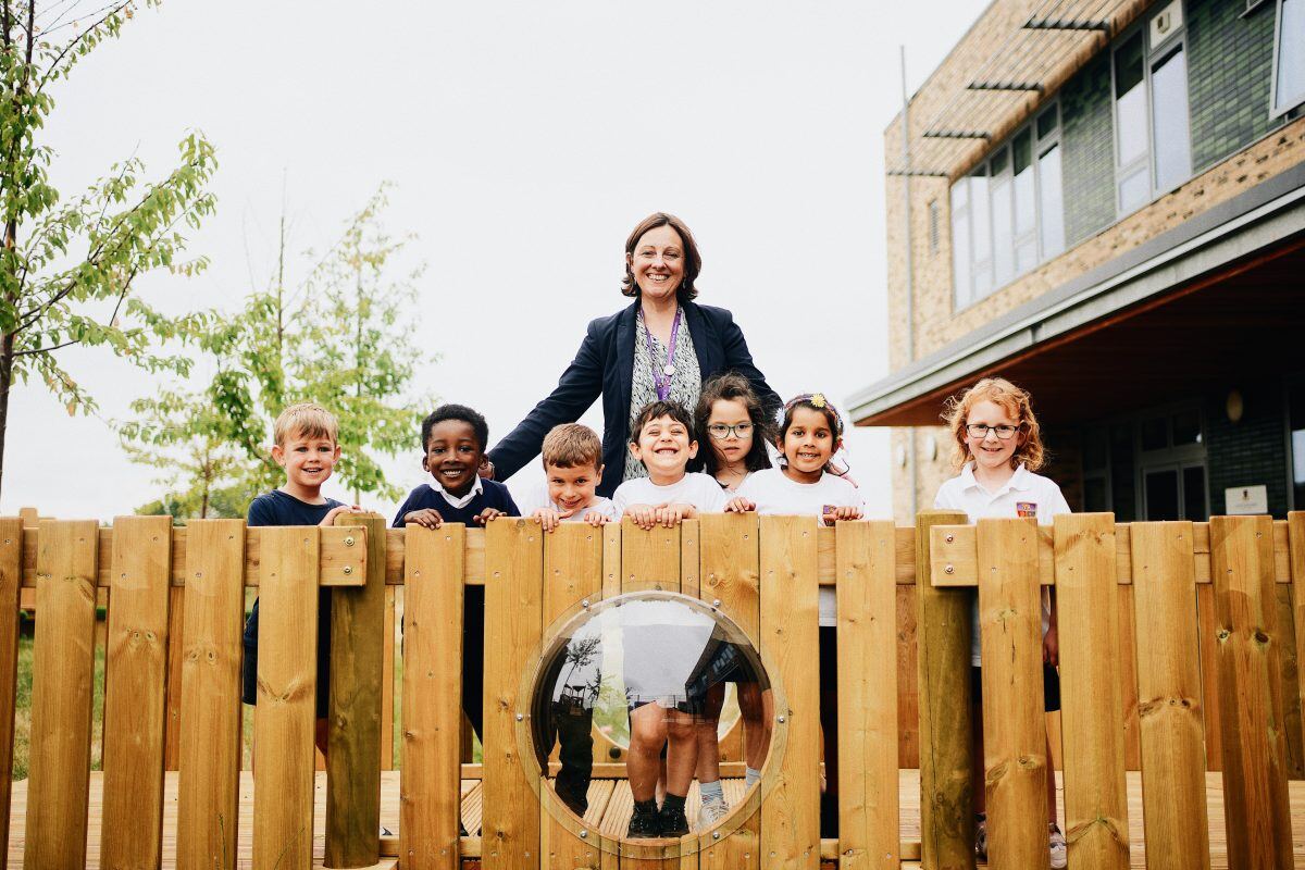 Head Teacher and kids standing on their new play equipment