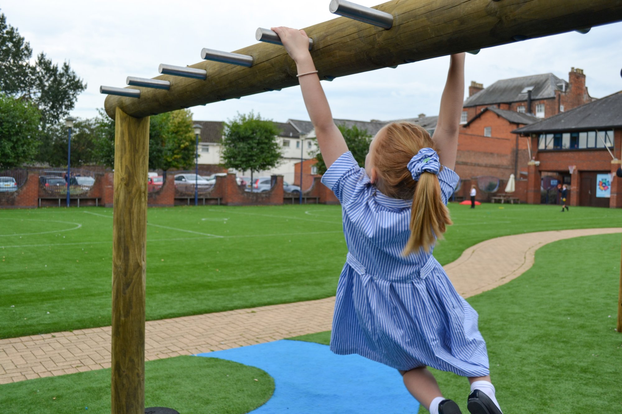 Girl in blue dress swinging on monkey bars